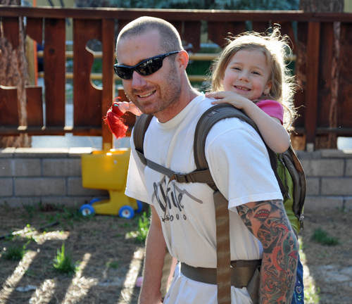 Brian wearing Zoe in the Onya Baby carrier in the back carry position