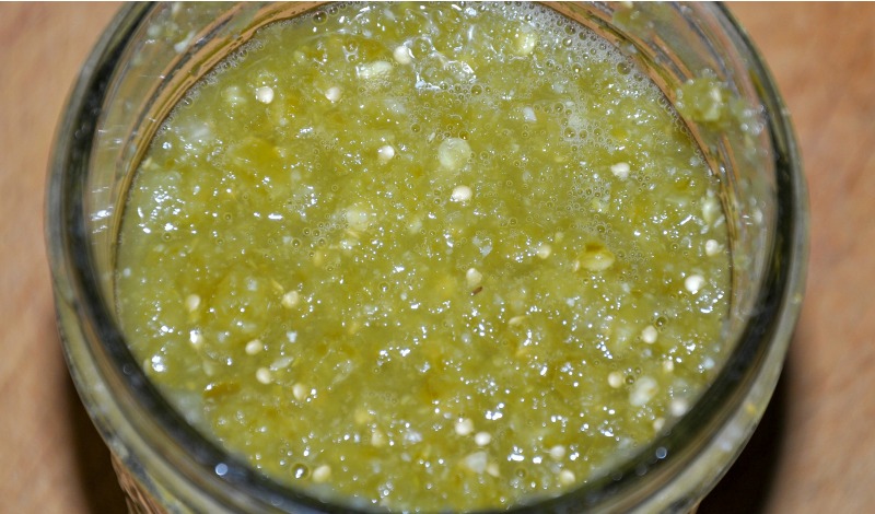 Top view of salsa verde fermenting in a glass jar on a cutting board