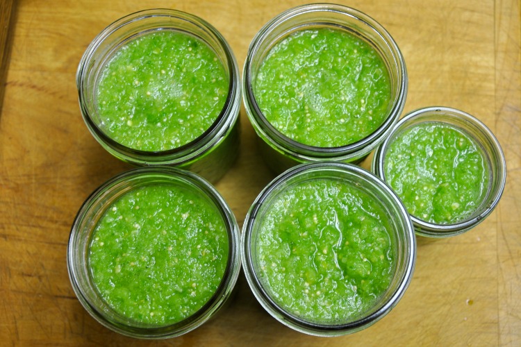 Five glass jars of freshly made salsa verde ready to ferment
