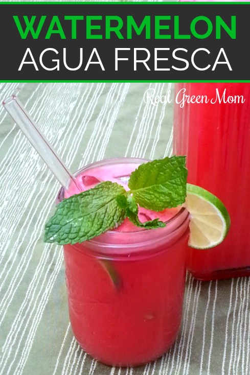 Watermelon agua fresca in pint sized mason jar with glass straw, garnished with mint and lime in front of full pitcher