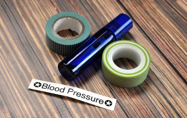 Blue roller bottle, washi tape and label that reads blood pressure on a wood table