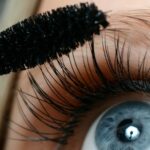 Close up of woman with blue eyes applying black mascara