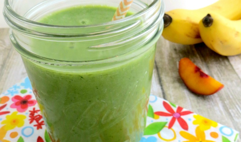 Peach & Pineapple green smoothie on wood table with peach slice and bananas