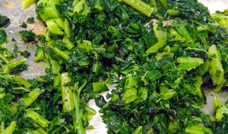 Chopped kale being sauteed in a stainless steel pan