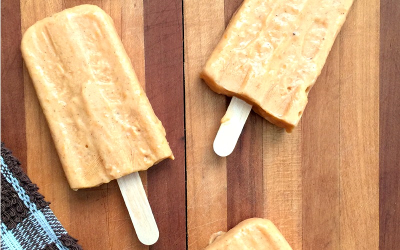 Pumpkin popsicles spread out on a wood cutting board