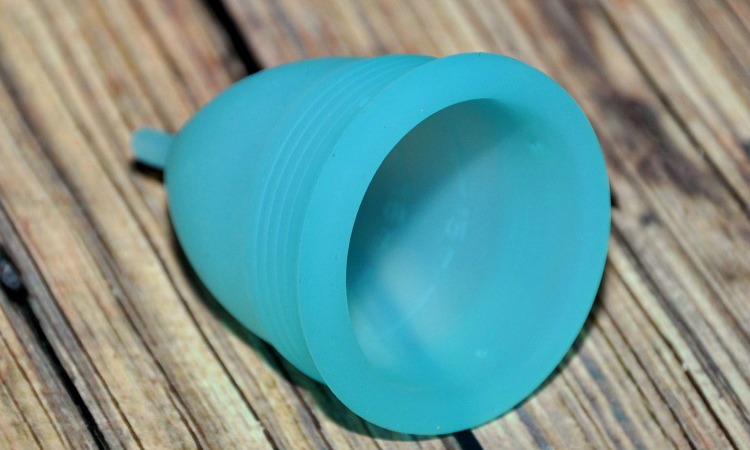 Blossom Menstrual cup lying on a wood table on its side