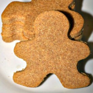 Close up of gingerbread man cookie leaned against a stack of three more on a white plate