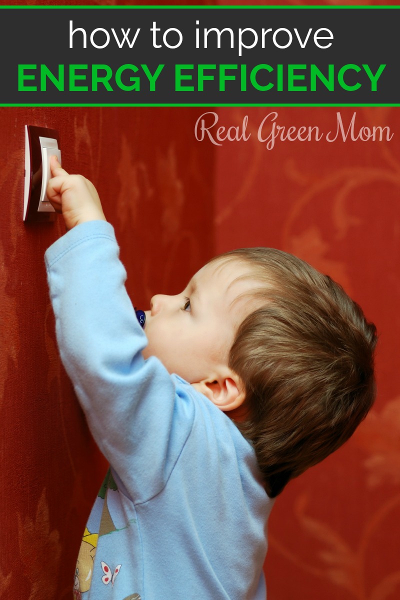 Little boy in blue pajamas turning on the light switch on a red wall