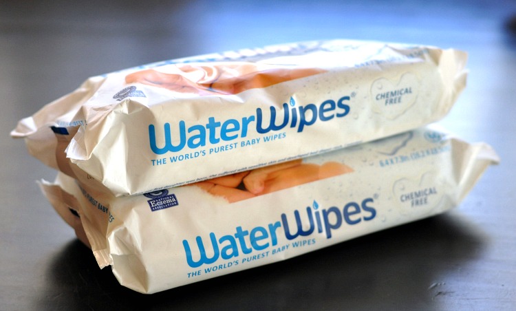 Two packages of WaterWipes stacked on a brown wood table