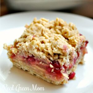 Close of of pomegranate apple pie bar with crumble topping on white dessert plate