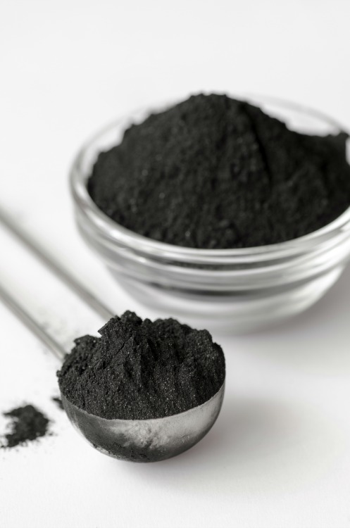 Activated charcoal in a glass bowl and measuring spoon
