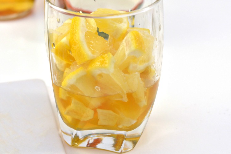 Lemon wedges added to glass with honey, apple cider vinegar and ginger