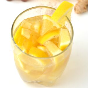 Glass of homemade lemon ginger tonic with a wedge on the rim