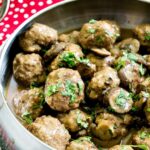 Silver bowl of Salisbury Meatballs with mushrooms on a red and white polka dot place mat with silver spoon
