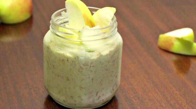 Matcha Overnight oats in a jar topped with apple slices on a table with extra apple slices