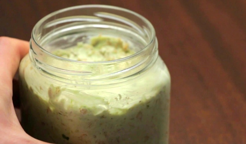 Hand grabbing matcha overnight oats jar off table to put in refrigerator
