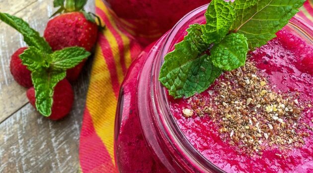 Berry beet smoothie in mason jar on wood table with fresh berries