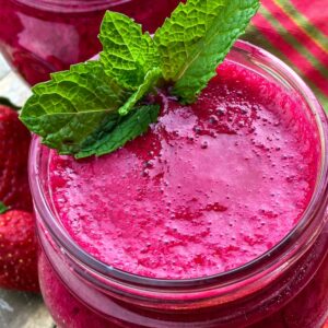 Close up of top of berry beet smoothie in a mason jar garnished with a mint sprig