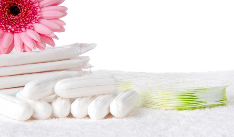 Organic pads and tampons on a white towel with pink flower