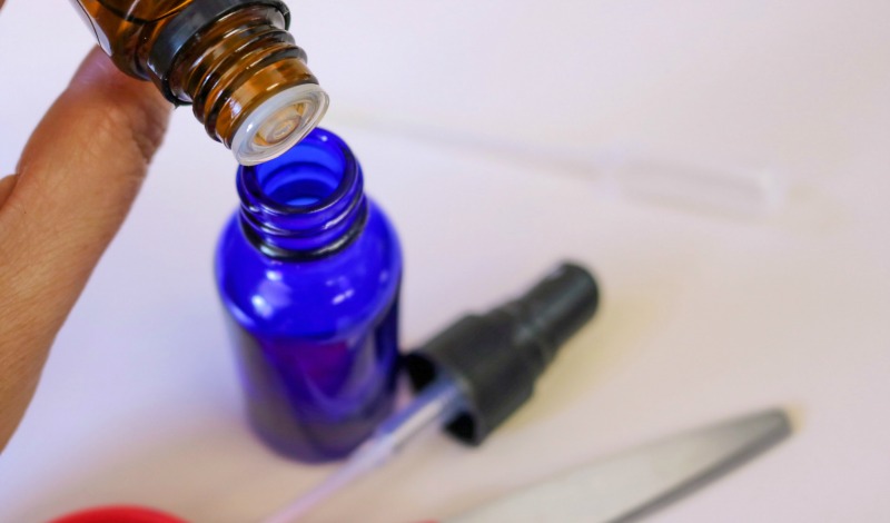 Essential oils being added to a 2 ounce blue glass spray bottle